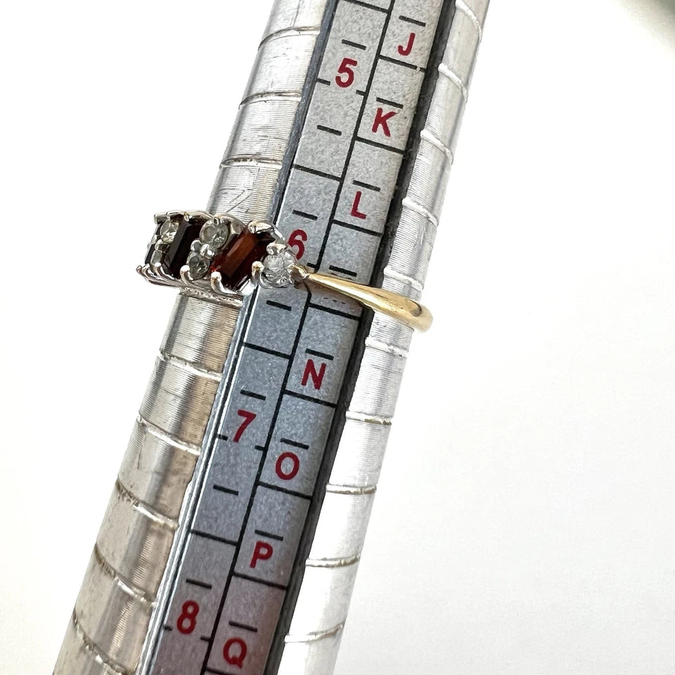 Gold rings displayed on a ruler for size comparison against a white background