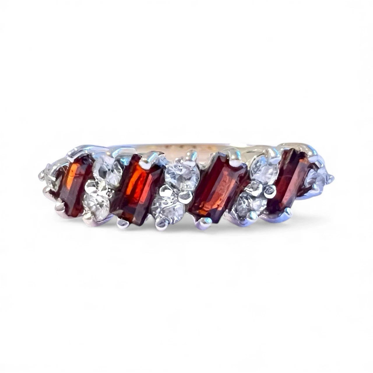 Gold ring with red and clear gemstones on a white background. Close up front view 
