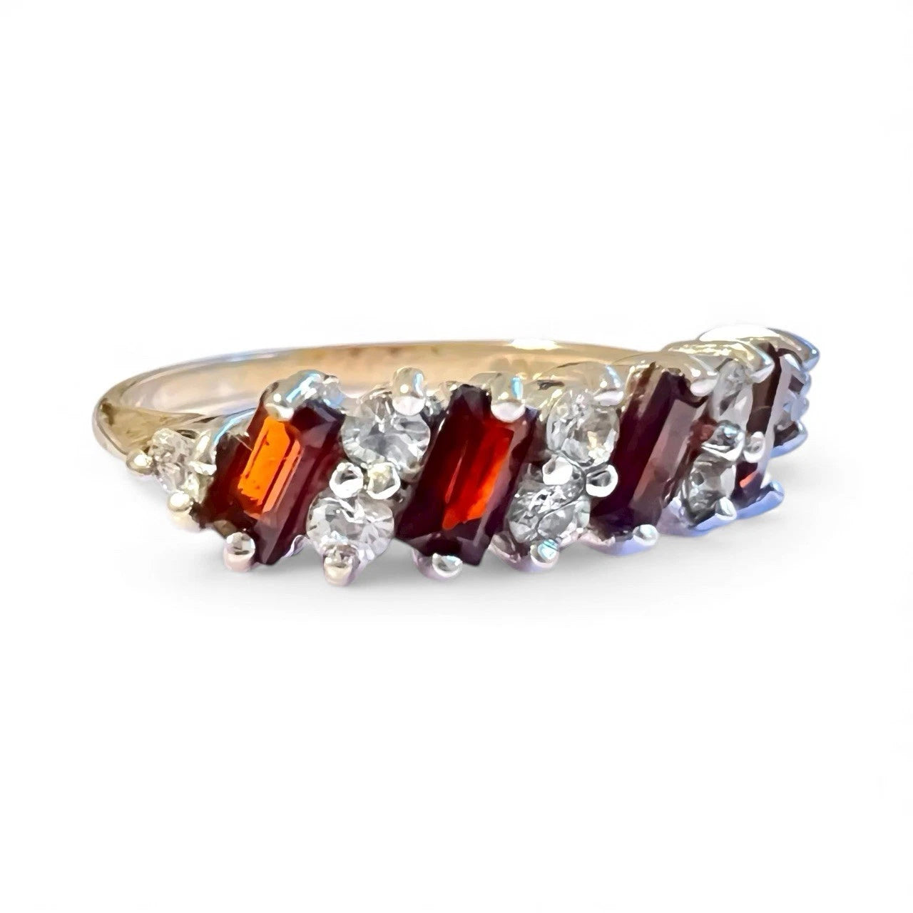 Ring with red and clear gemstones on a white background. Close up side view 