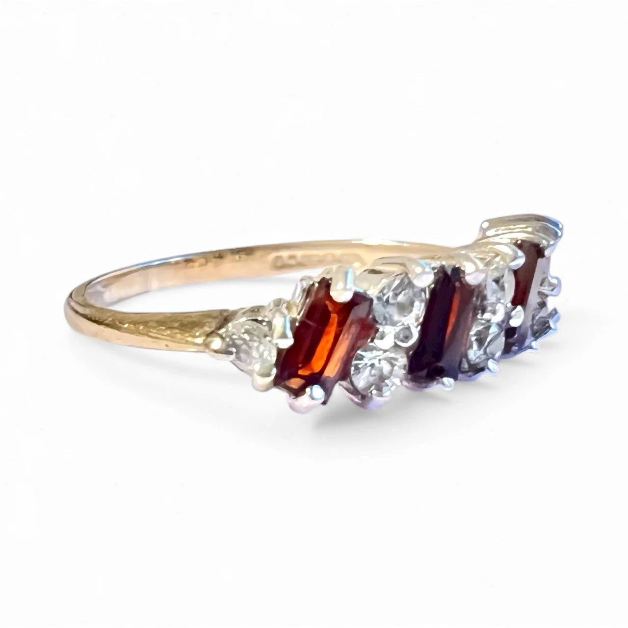 Gold ring with red and clear Cubic Zirconia on a white background