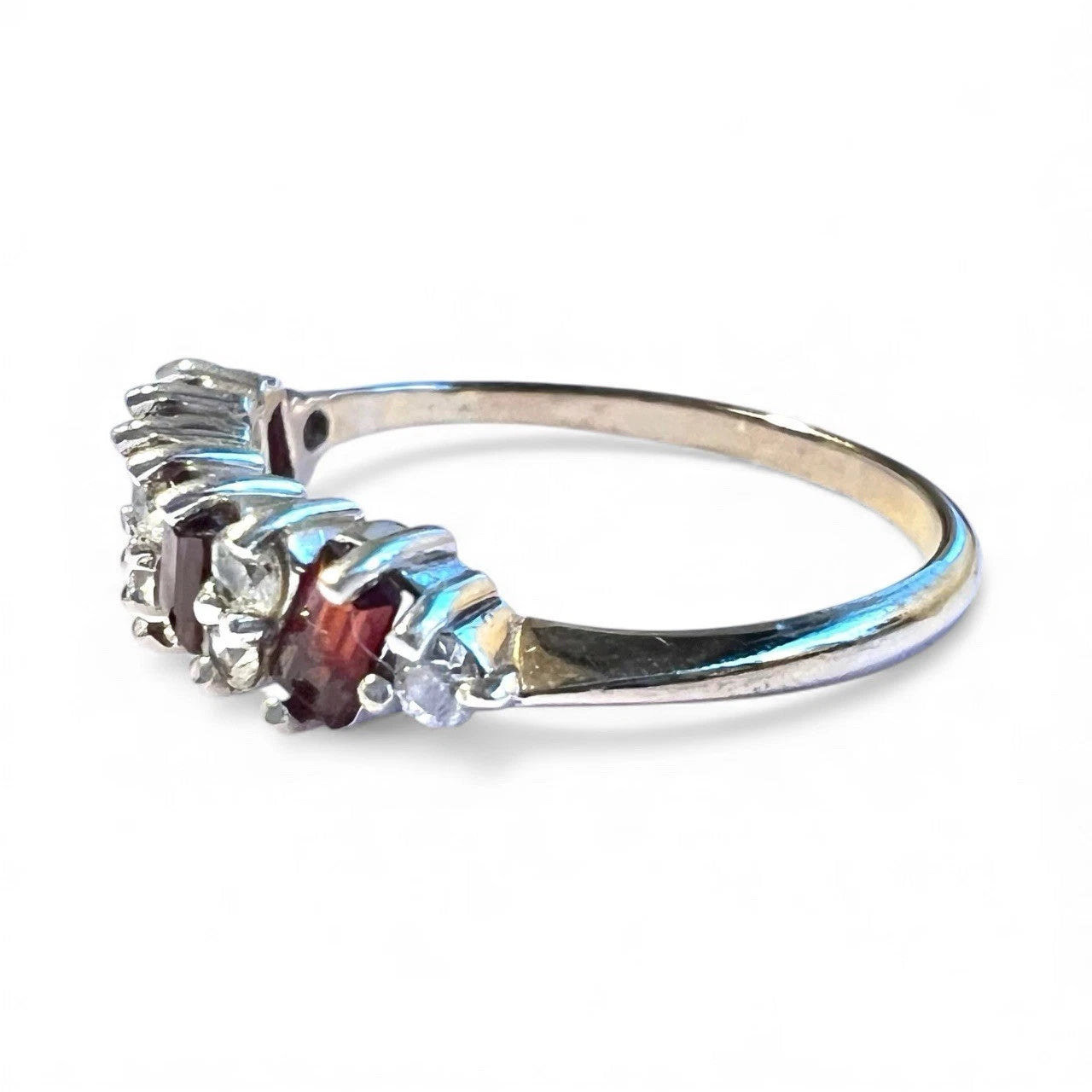 Gold ring with red and clear cubic zirconia gemstones on a white background
