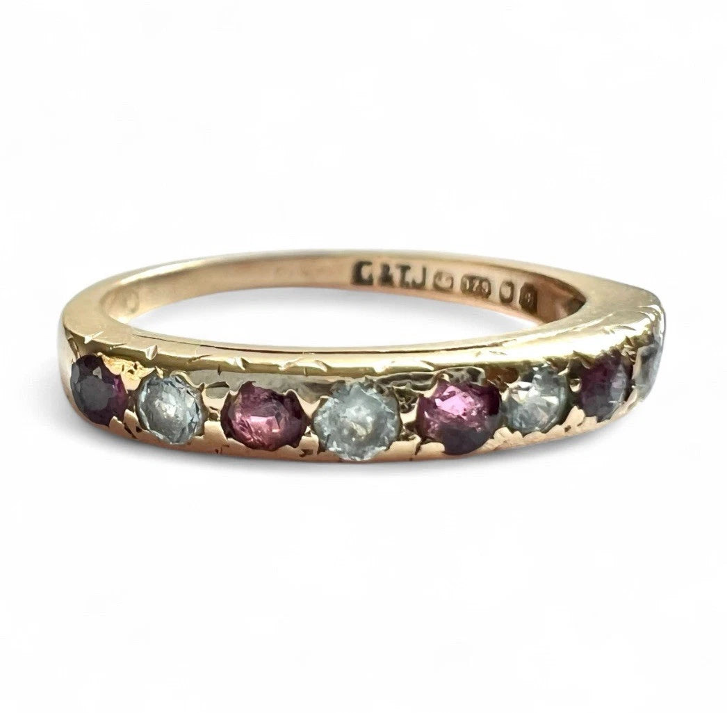 Gold ring with embedded ruby and cubic zirconia gemstones on a white background