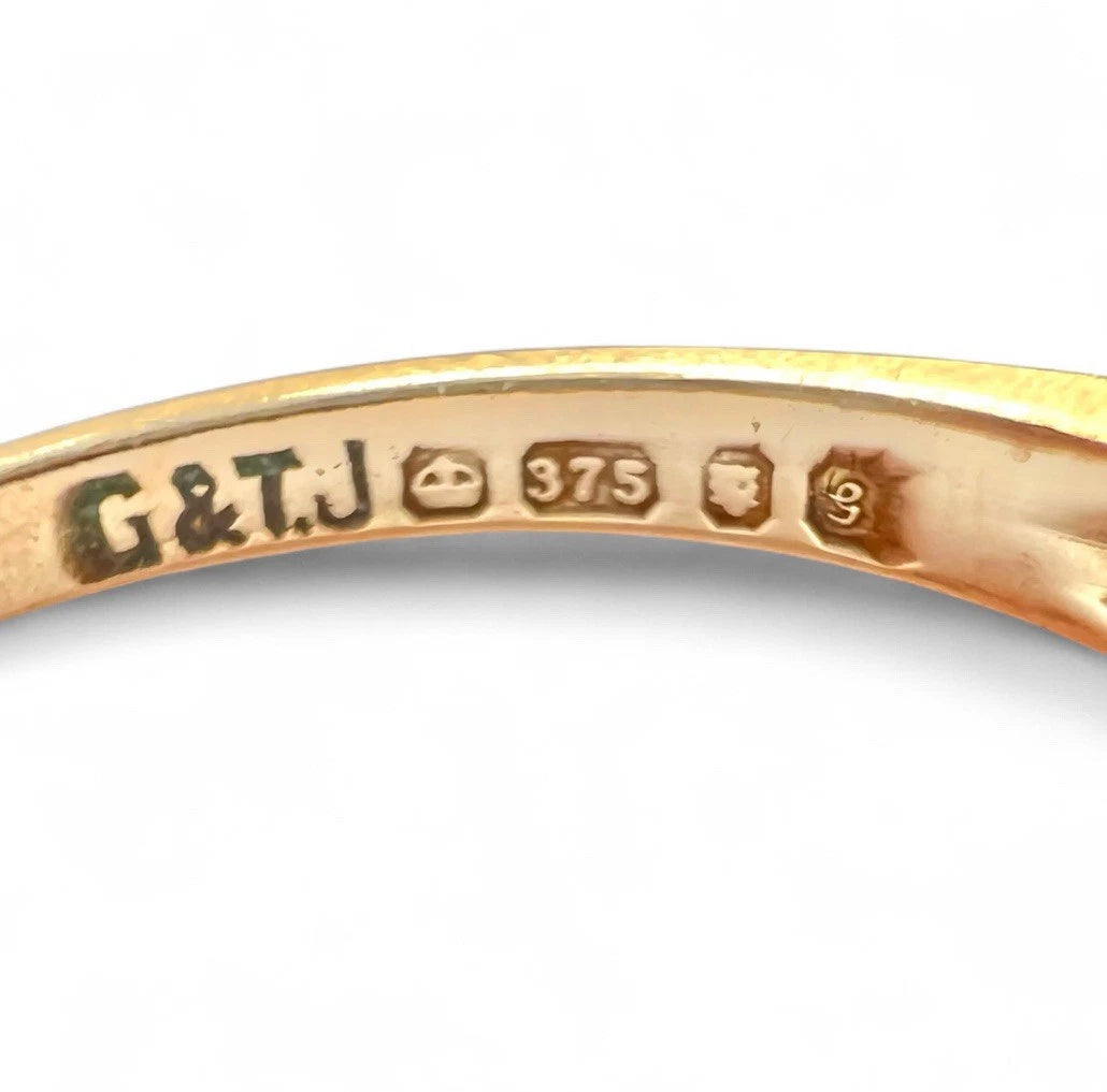Gold ring with 'G&J' branding and hallmark on a white background
