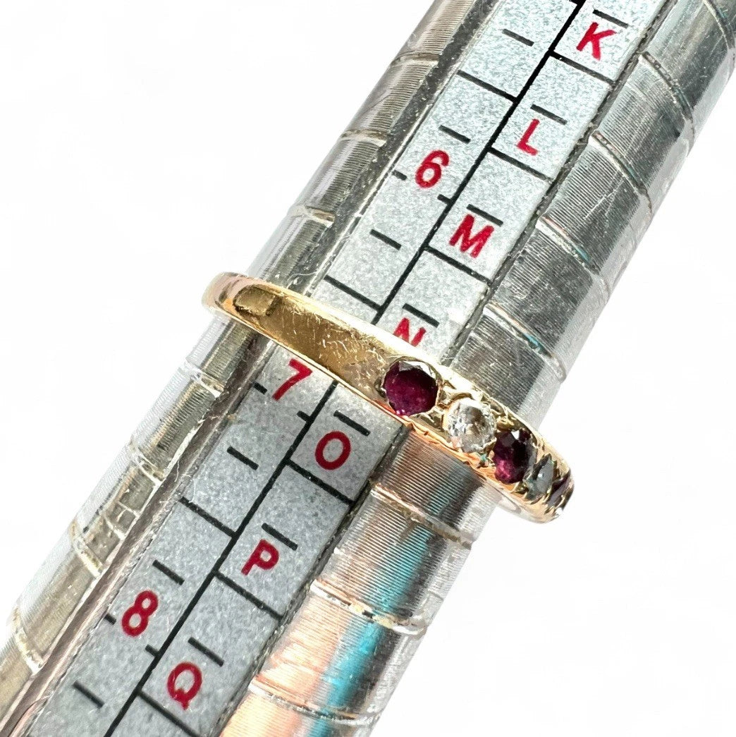 Gold ring with red gemstones on a silver ruler with measurement markings