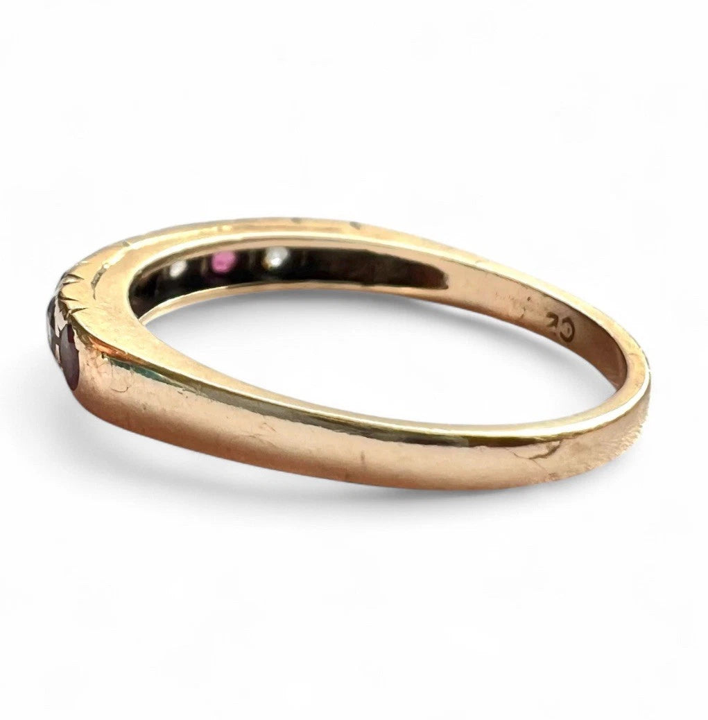 Gold ring with ruby and CZ gemstones on a white background close up side view of gold band 