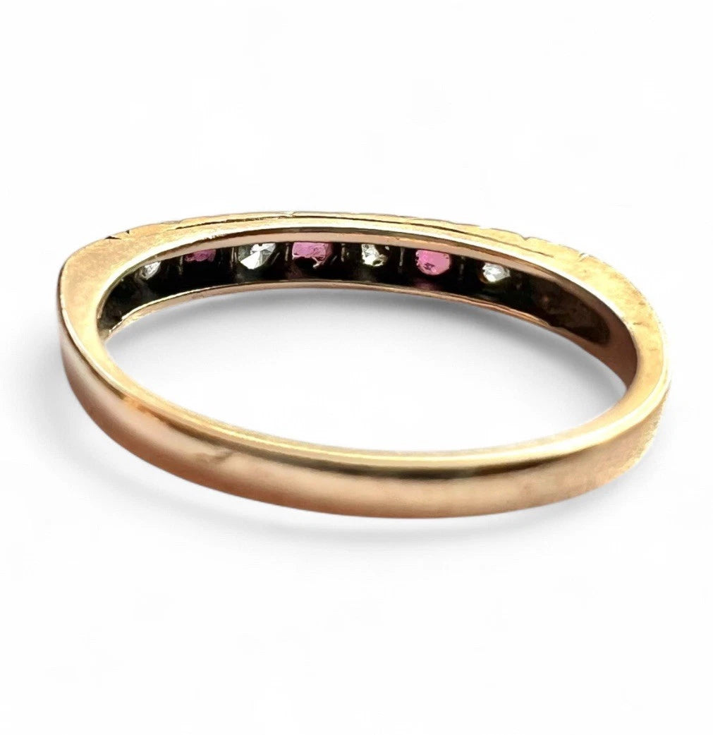 Gold ring with embedded ruby and CZ stones on a white background, close up rear view of setting and gold band