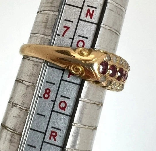 Gold ring with red ruby and diamond gemstones on a metal ruler