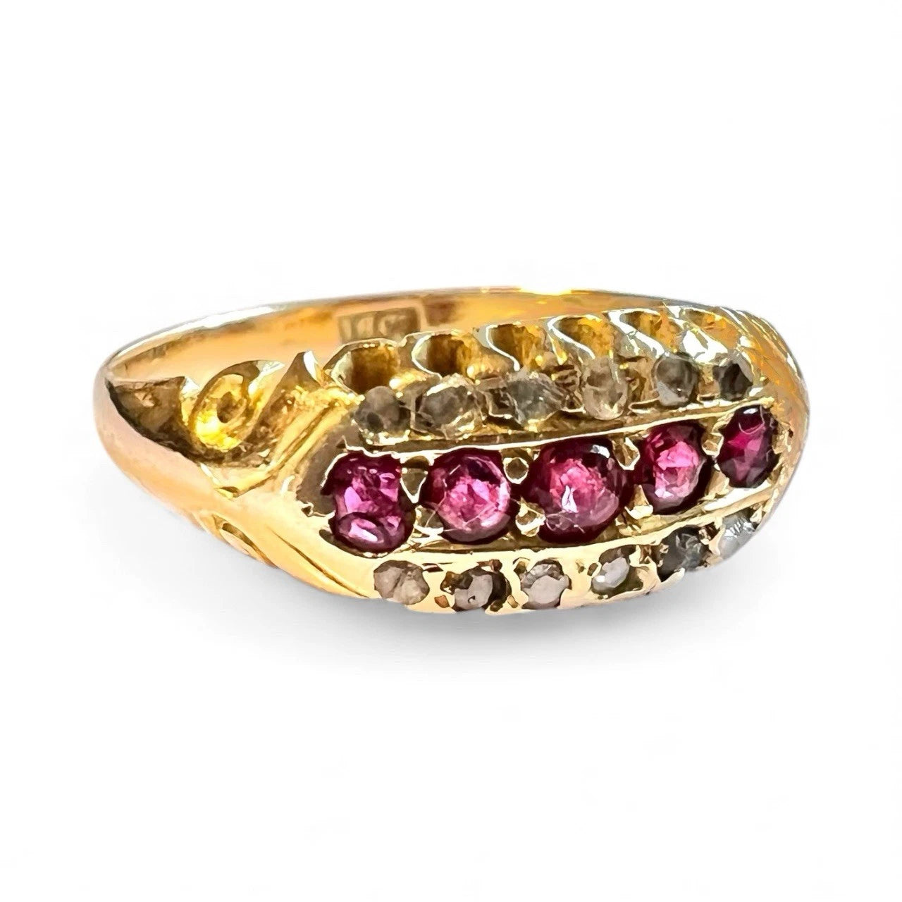 Edwardian gold ring with red rubies and diamond gemstones on a white background close up side view 