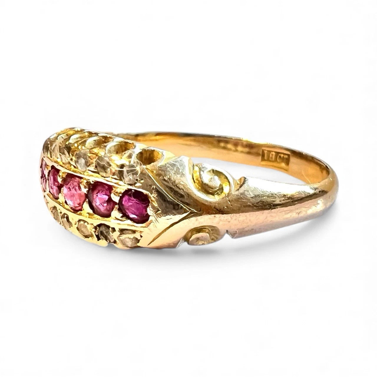 Edwardian gold ring with red rubies and diamond gemstones and detailed band on a white background close up 