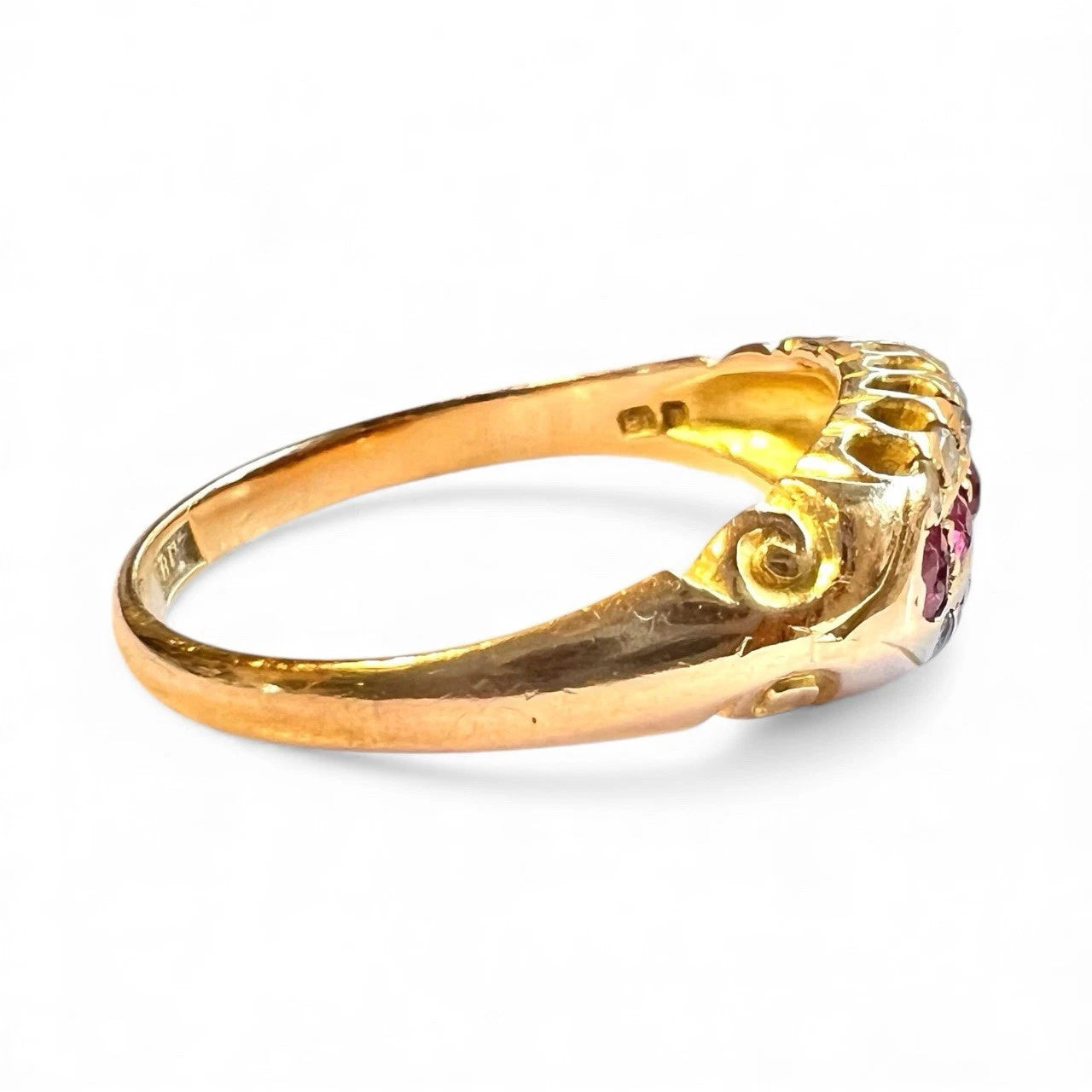 Antique gold ring with a rubies and diamonds on a white background side view of gold band 