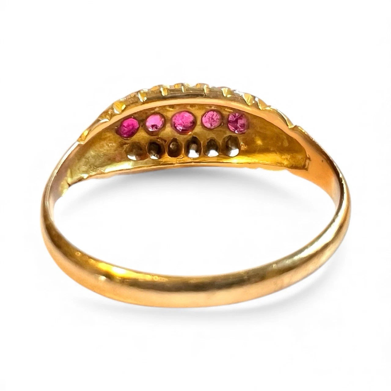 Gold ring with red ruby and diamond gemstones on a white background close up rear view of setting and gold band 
