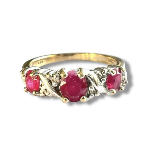 Vintage Gold ring with three red rubies and diamond gemstones on a white background, close up front view of setting 