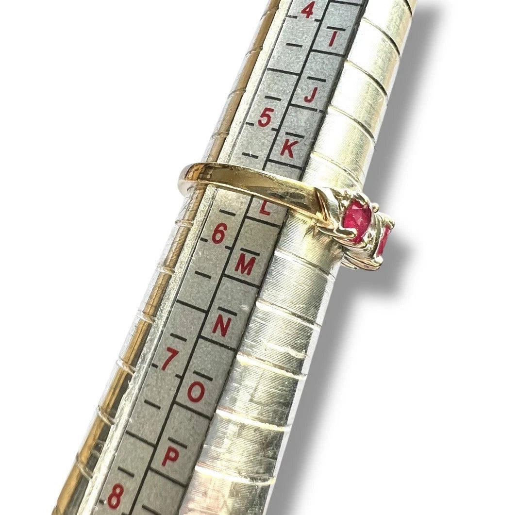 Gold ring with a red ruby gemstones on a ruler for size measurement
