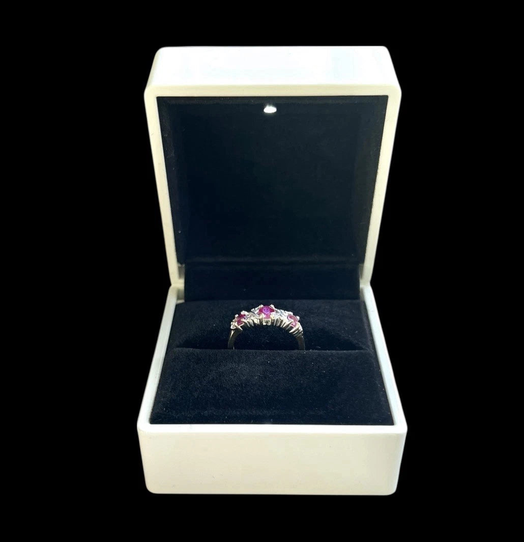 Ring with a three Ruby gemstone and diamonds in an open jewellery box on a white background