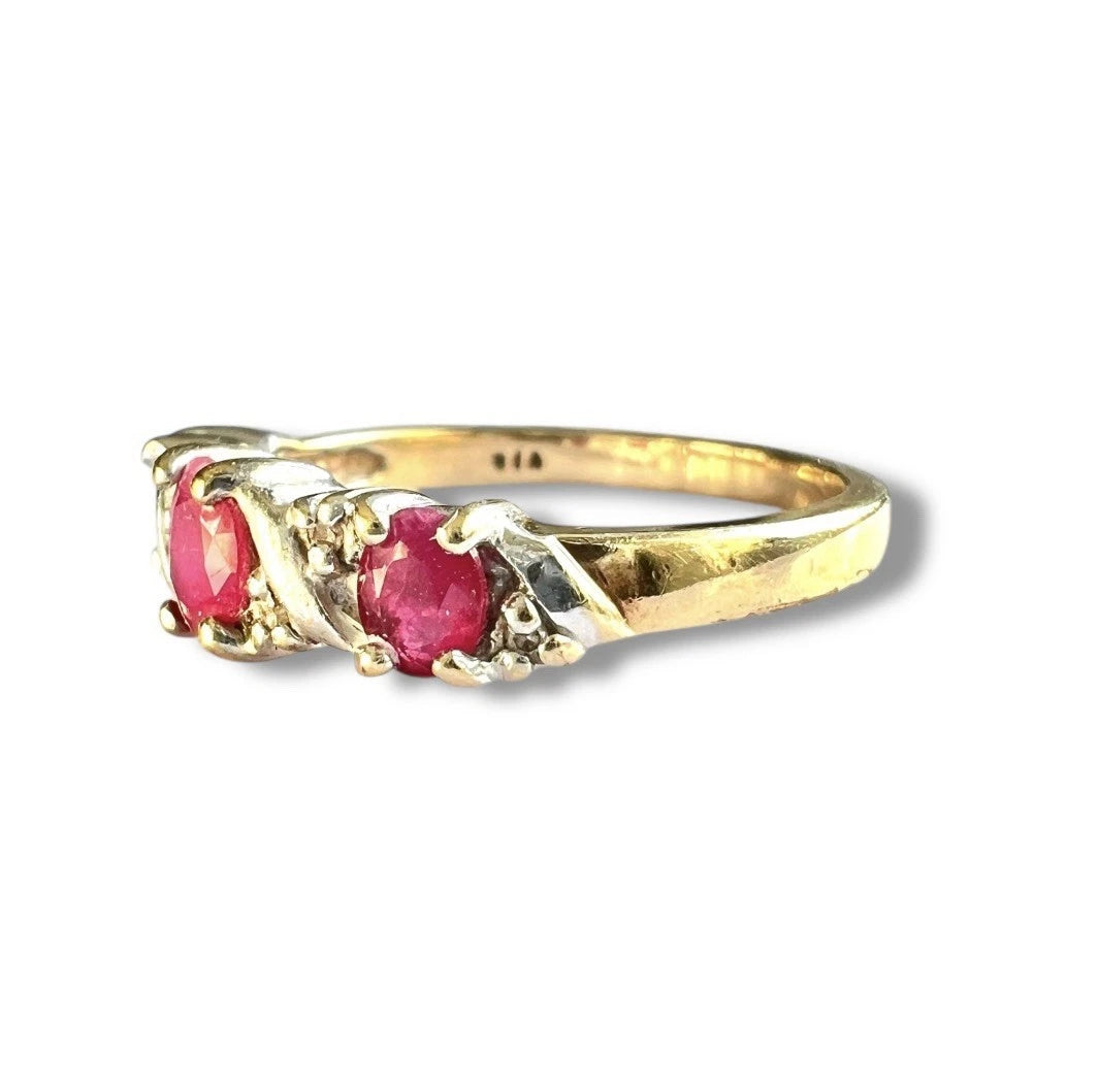 Gold ring with red ruby gemstones and diamonds on a white background close up side view. 