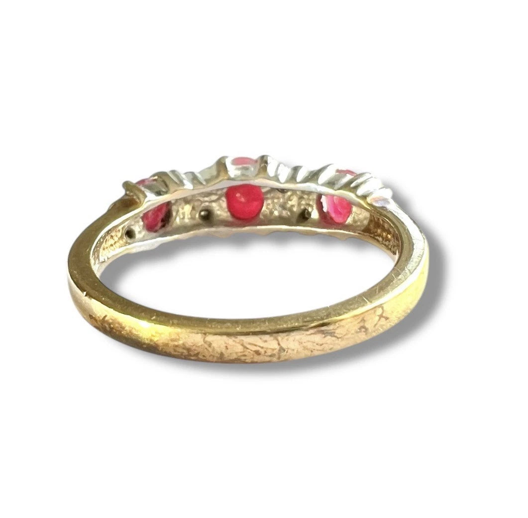 Vintage gold ring with three red ruby’s and diamonds on a white background, close up rear view of setting and gold band 