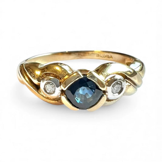 Gold ring with a blue sapphire gemstone and diamonds on a white background close up front view 