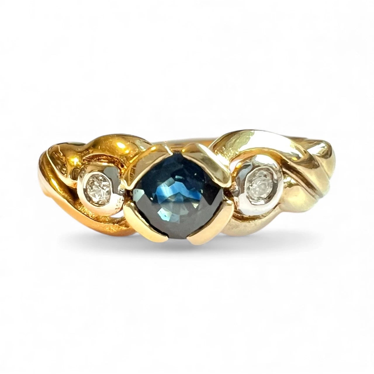 Close up front view of gold ring with a blue sapphire gemstone and two diamonds on a white background