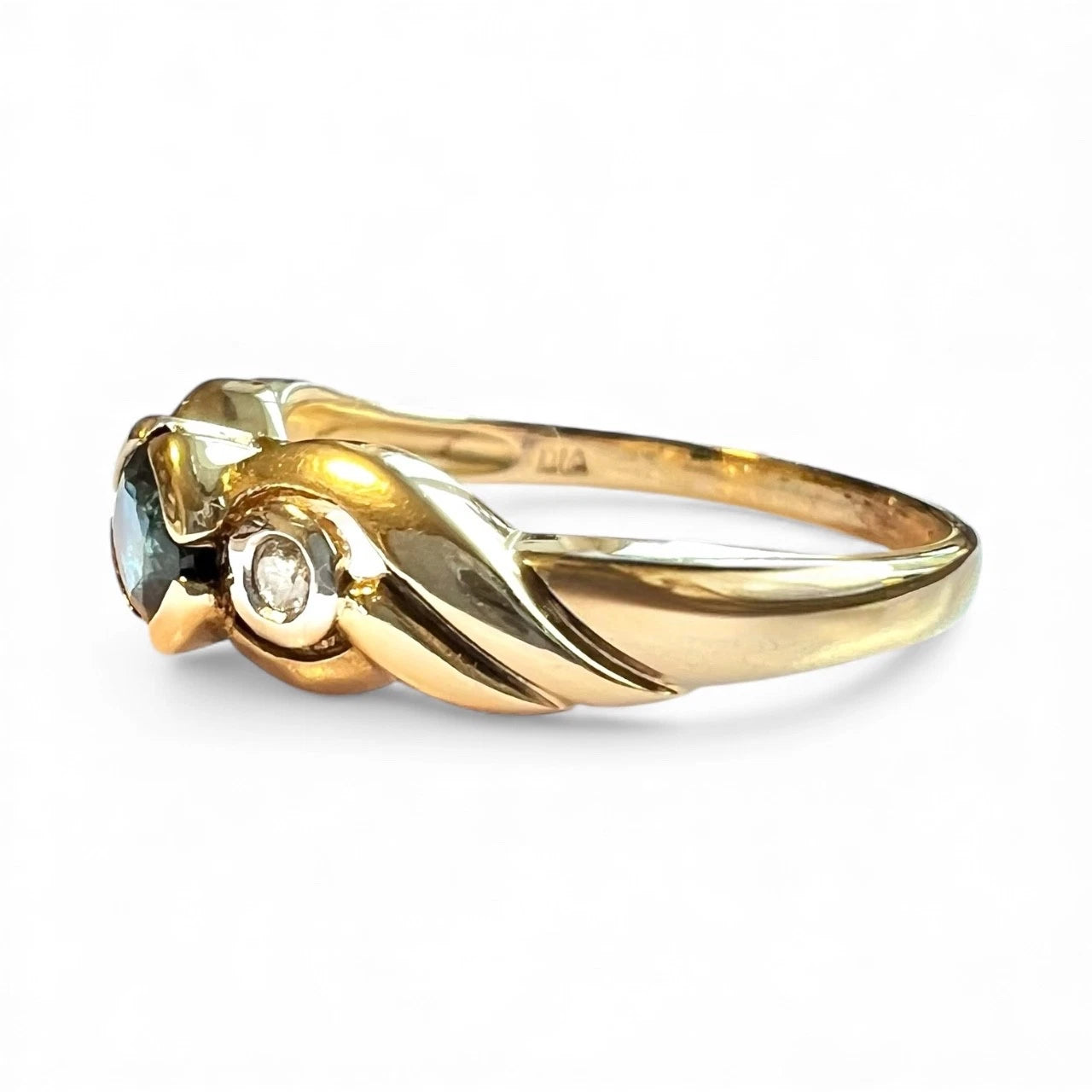 Vintage gold ring with sapphire gemstone and diamond on a white background, close up side view 