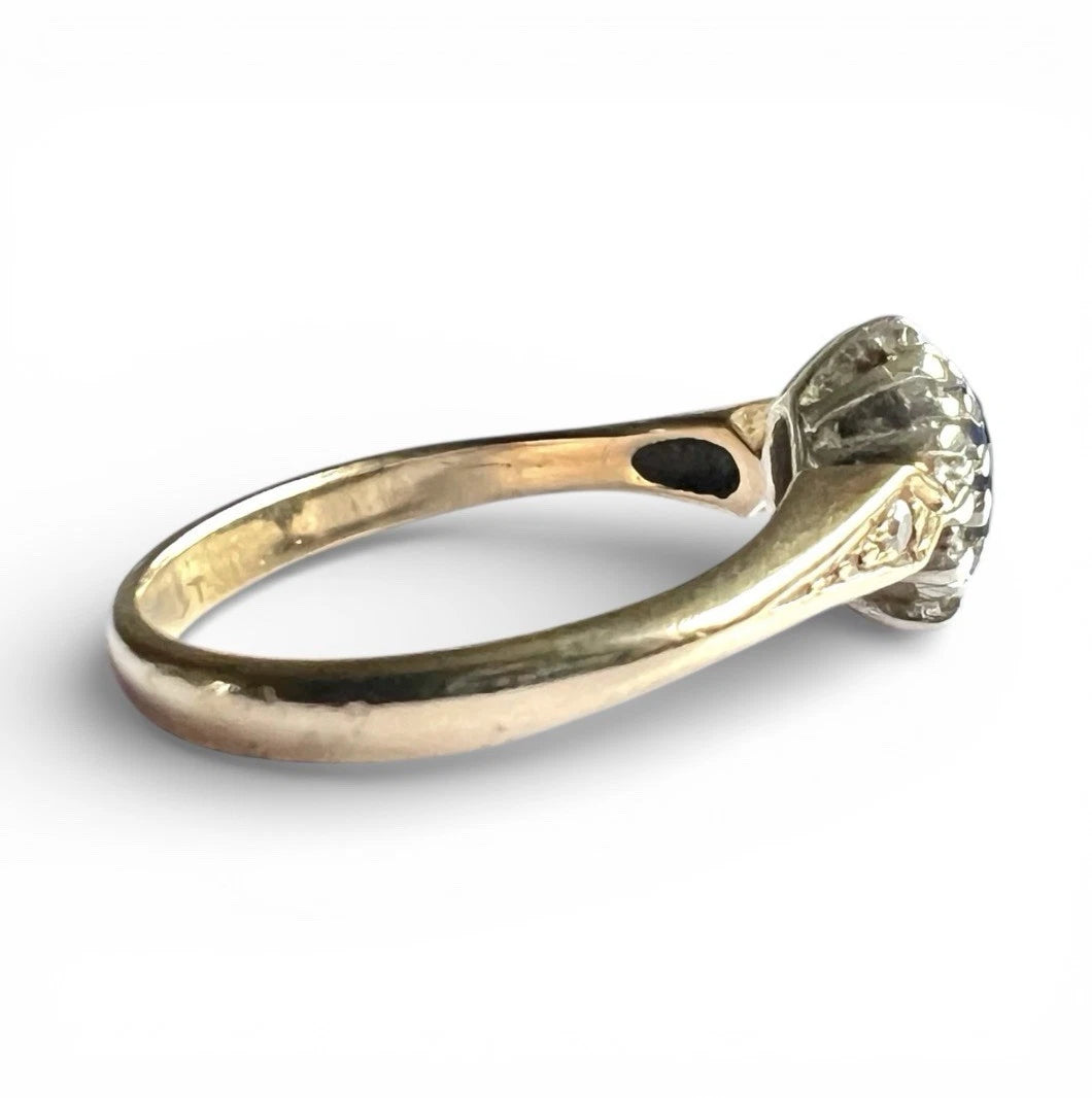 Gold ring with a sapphire and diamond halo on a white background