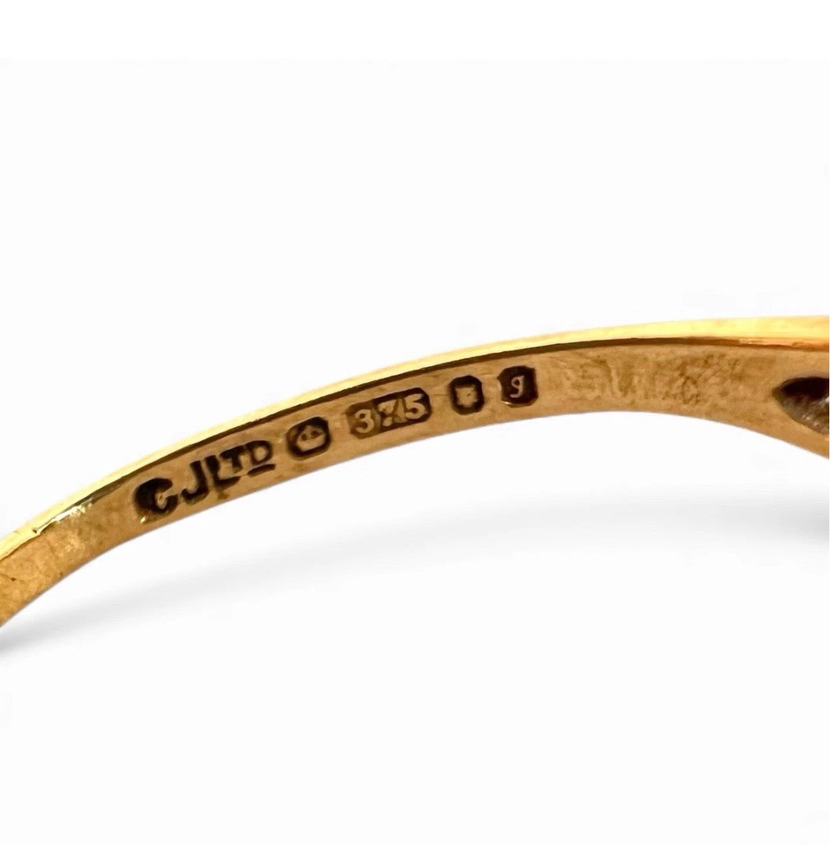 Gold ring with engraved hallmark on a white background