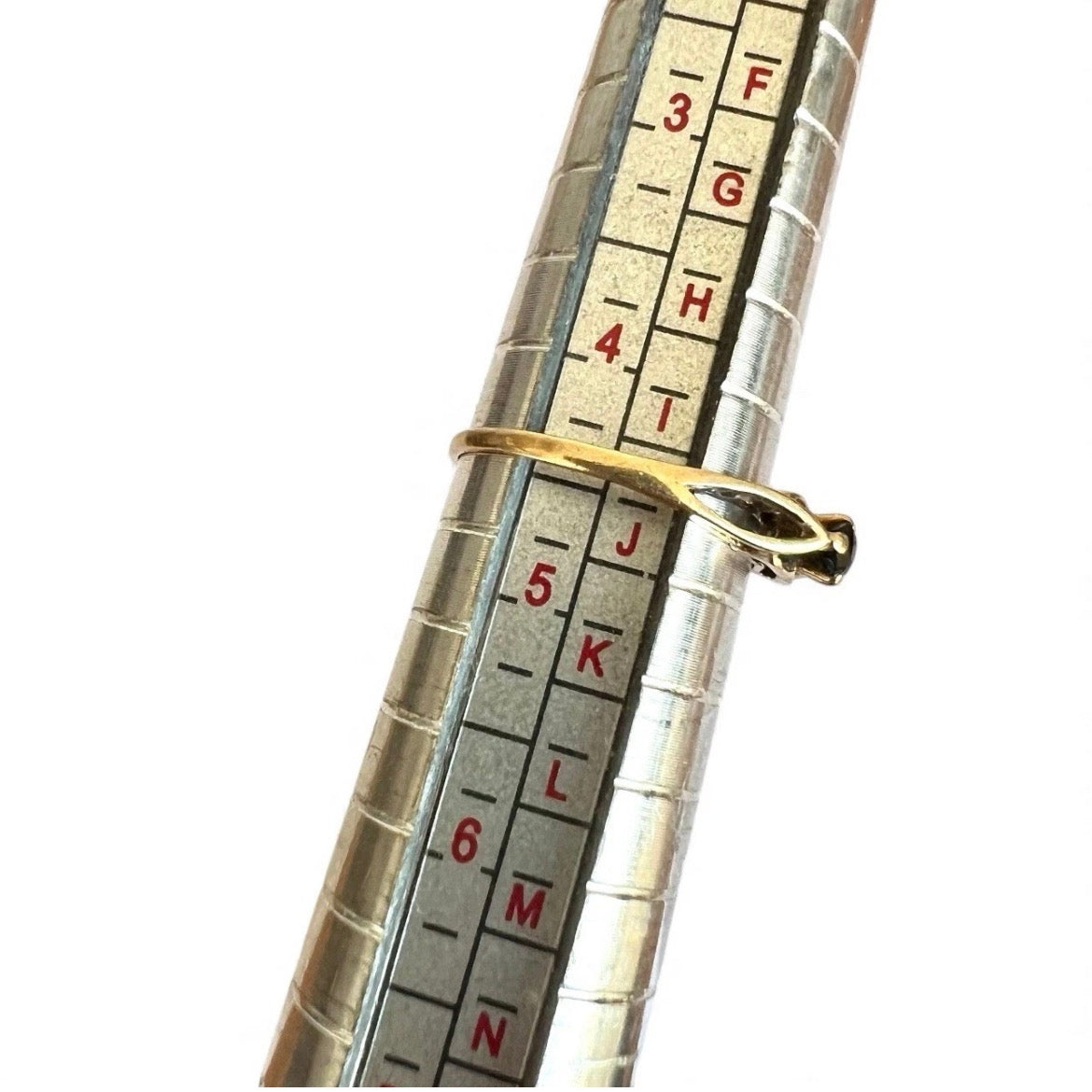 Close-up of a measuring tool with a gold ring on a white background