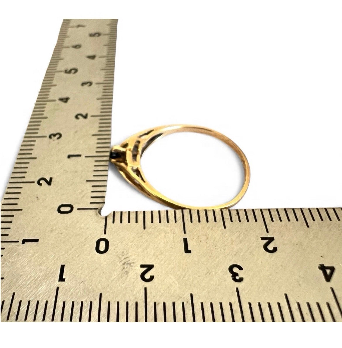 Gold ring next to a ruler on a white background