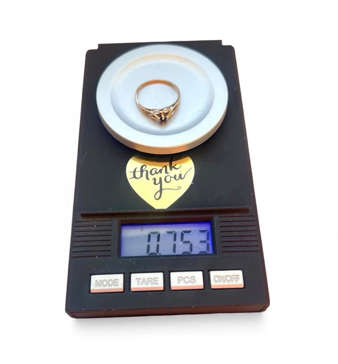 Gold ring on a digital scale with 'thank you' heart tag