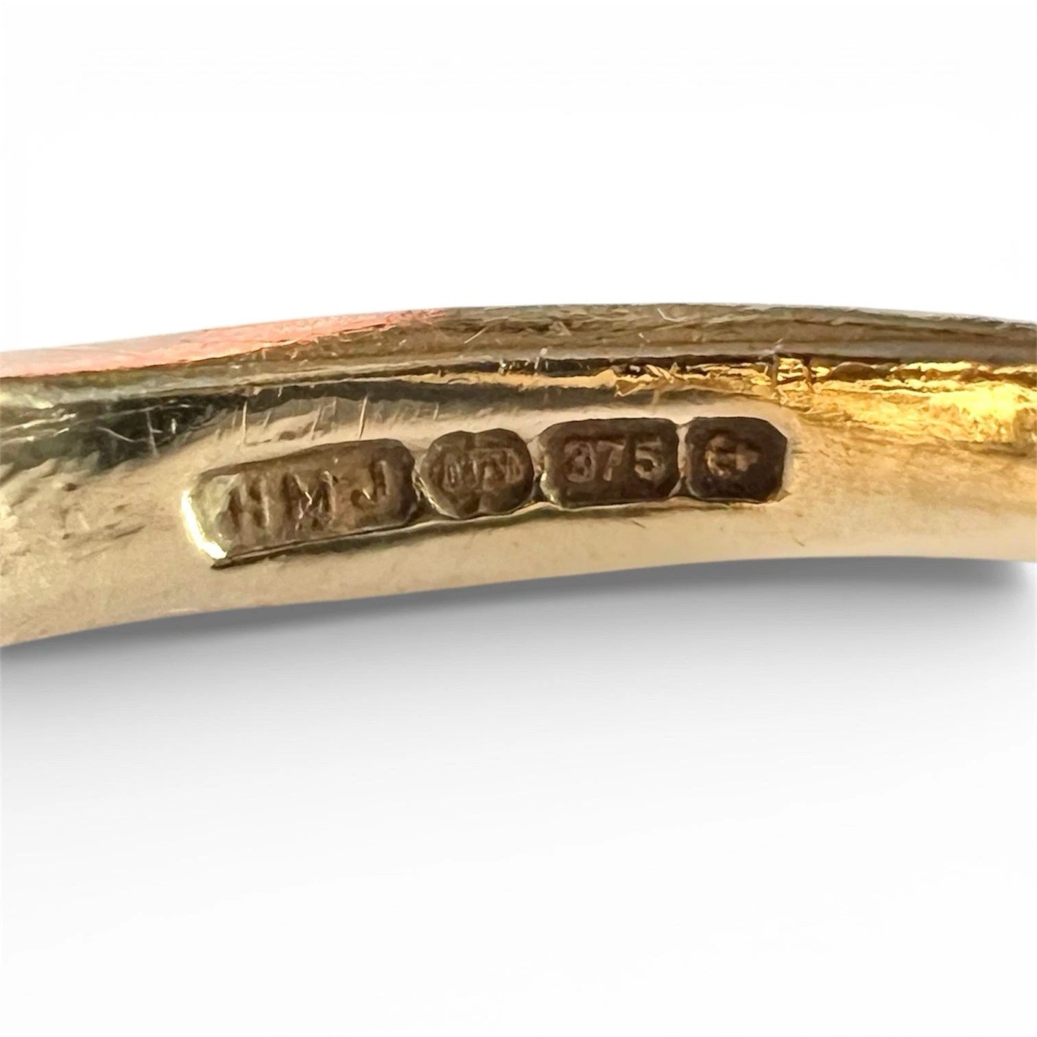 Gold ring with 'H M J' and '375' hallmark on a white background