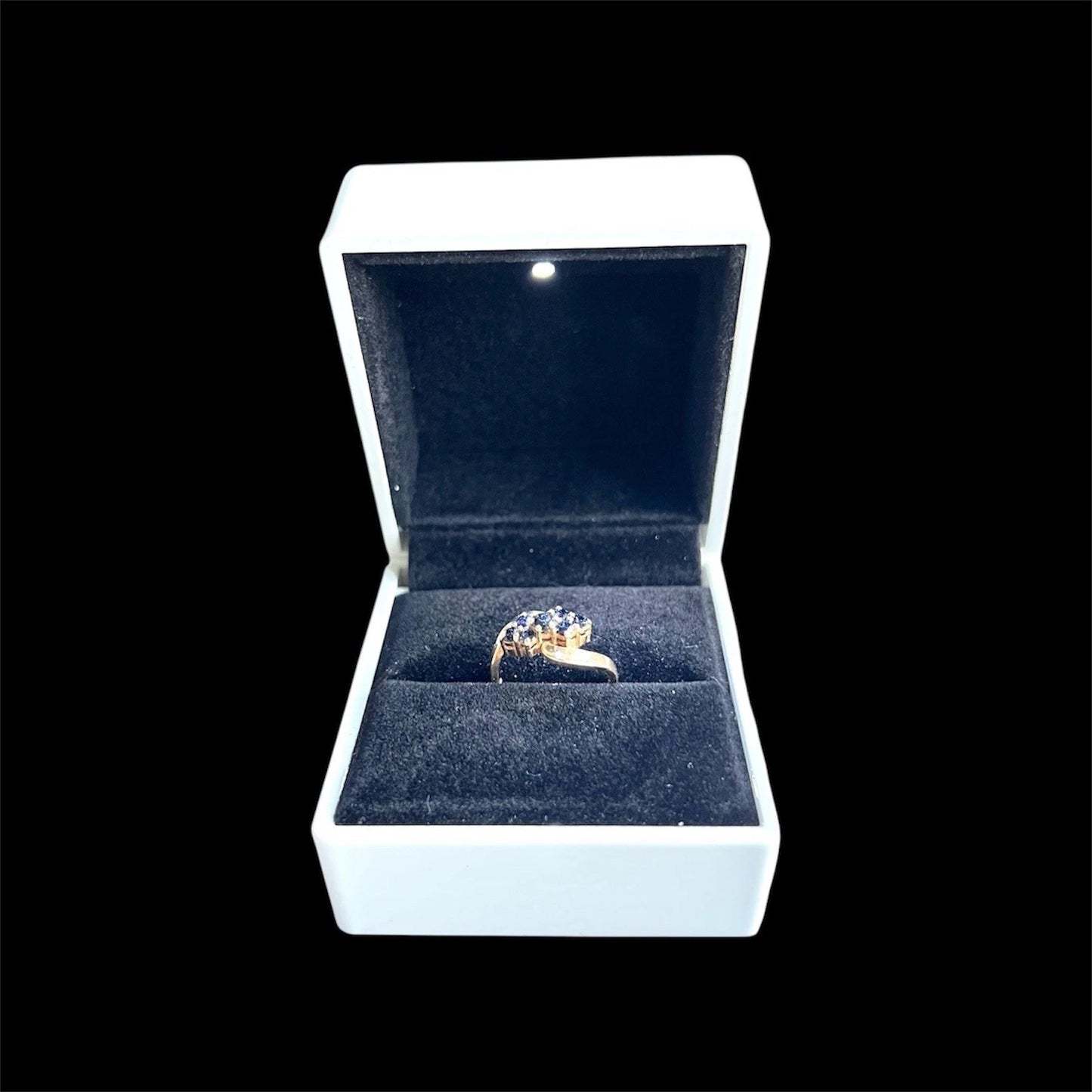 Gold ring with gemstones in an open jewellery box on a black background