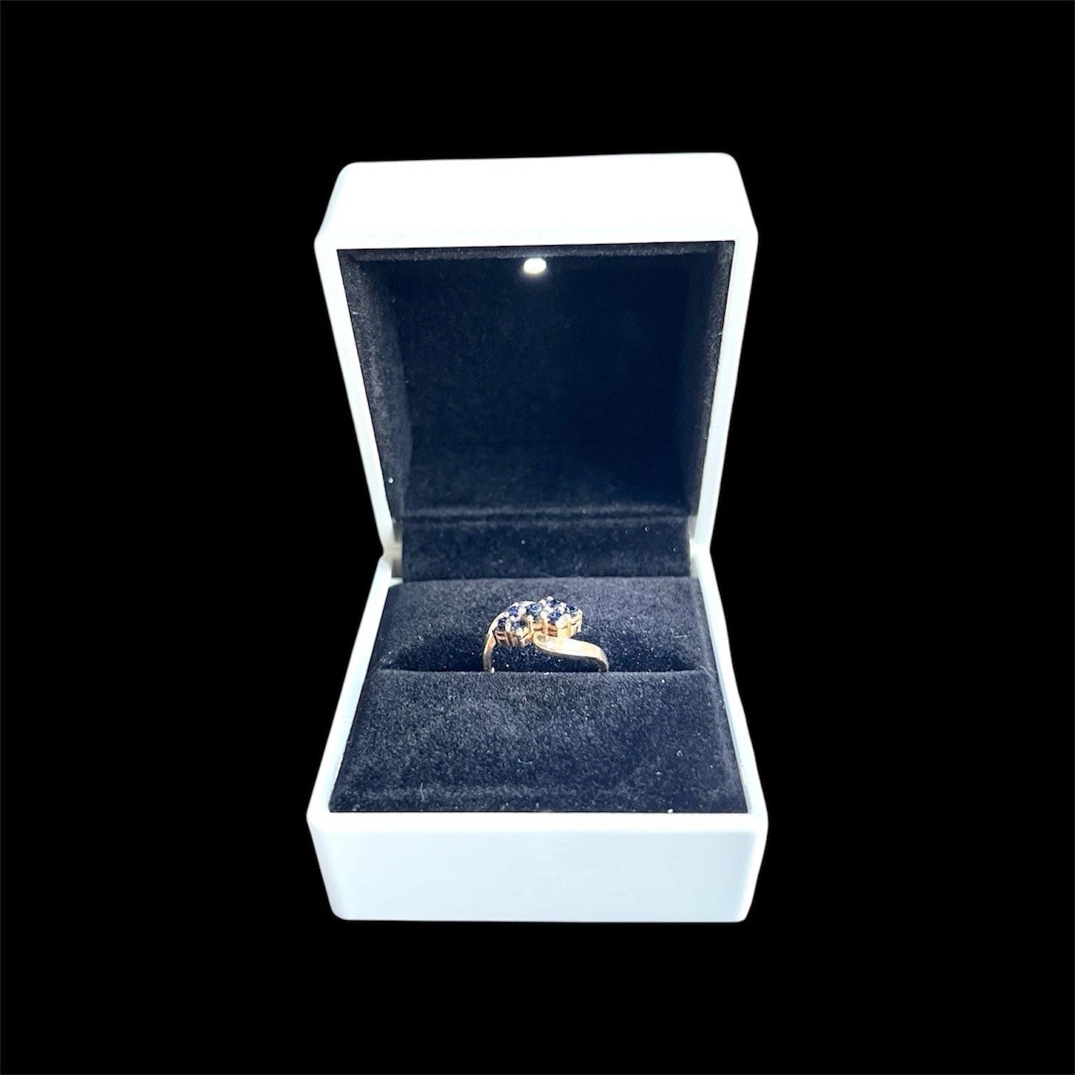 Gold ring with gemstones in an open jewellery box on a black background