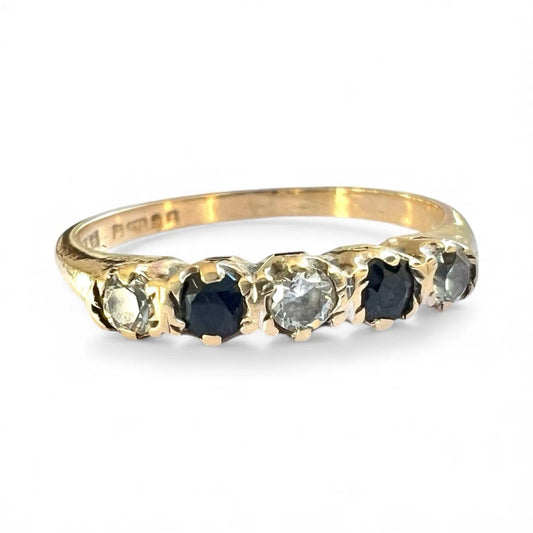 Gold ring with blue sapphire and cubic zirconia gemstones on a white background, close up front view of setting 