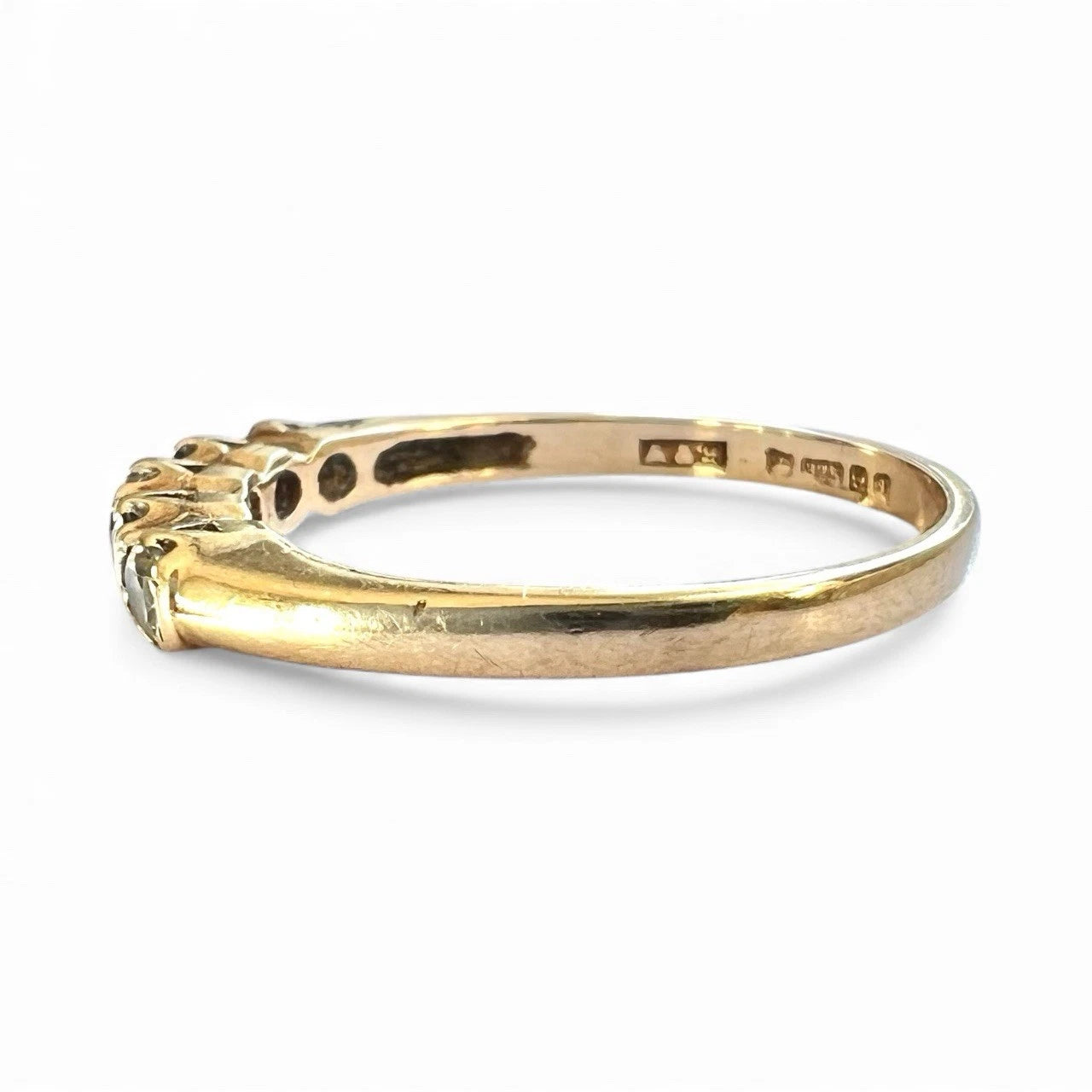 Gold ring with a sapphire and cubic zirconia on a white background, close up side view with hallmark visible 