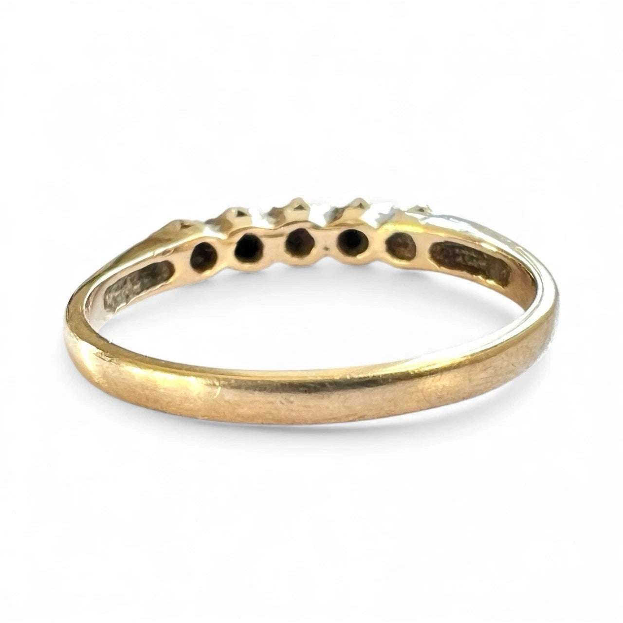 Gold ring with embedded sapphire and cubic zirconia stones on a white background, close up rear view of setting and gold band 
