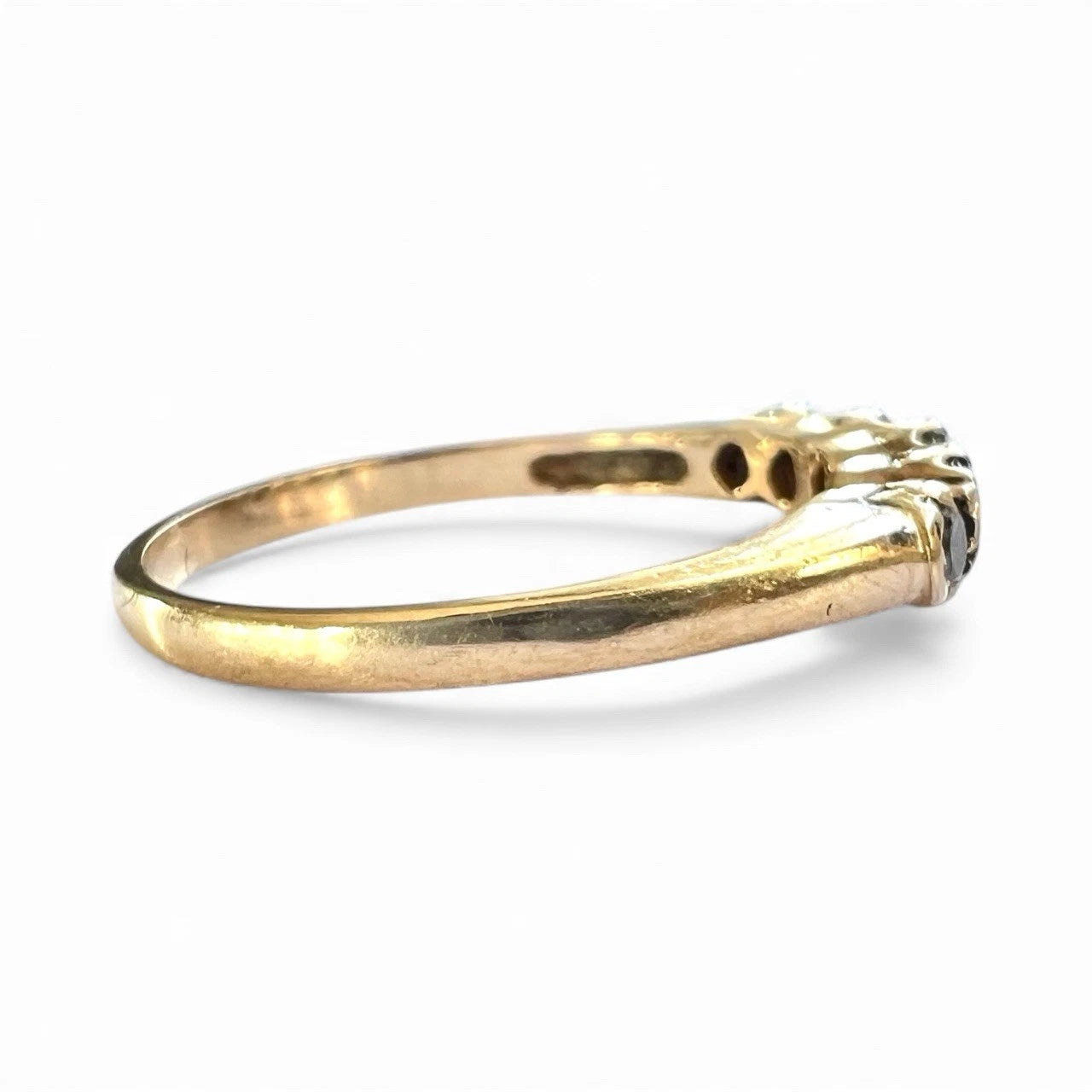 Gold ring with sapphire and cubic zirconia  stones on a white background, close up side view of gold band