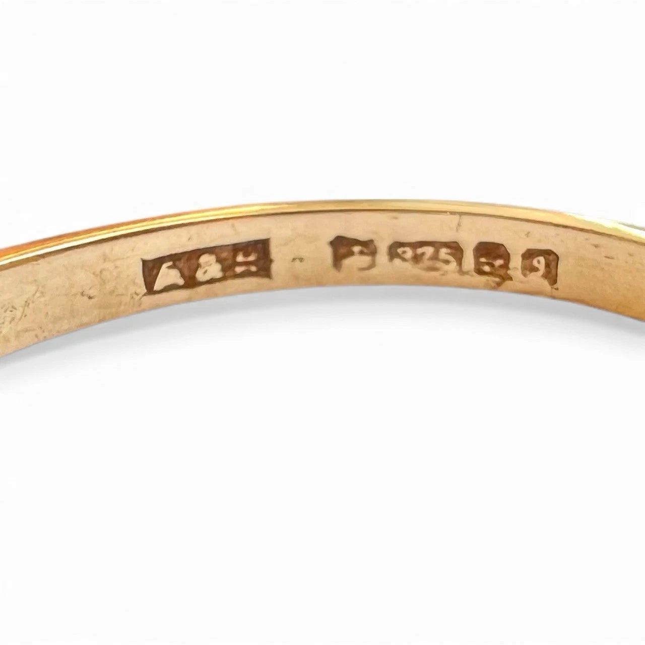 Close-up of a gold ring on a measuring tool on a white background