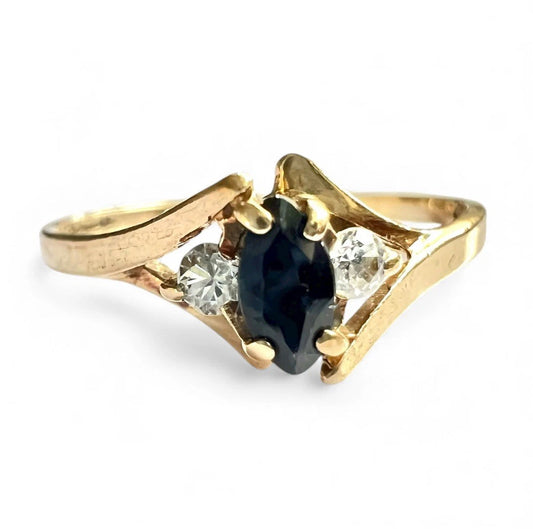 Gold ring with a central sapphire gemstone flanked by two diamonds on a white background