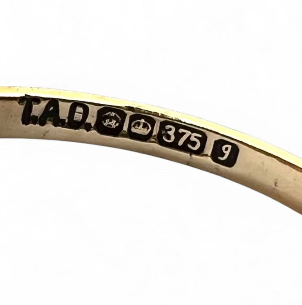 Gold ring with 'TAD' engraving and '375 9' hallmark on a white background