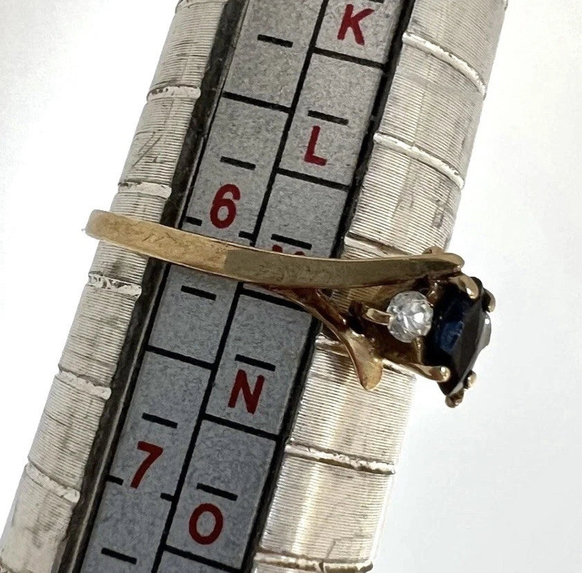 Gold ring with a sapphire gemstone on a ruler for size reference