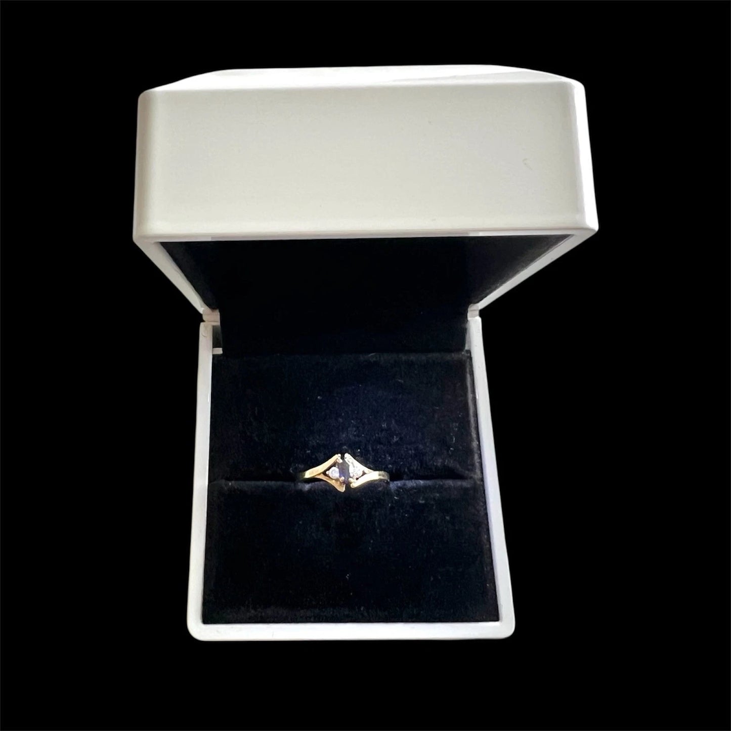 Gold ring with a sapphire and diamond in a white jewellery box on a white background