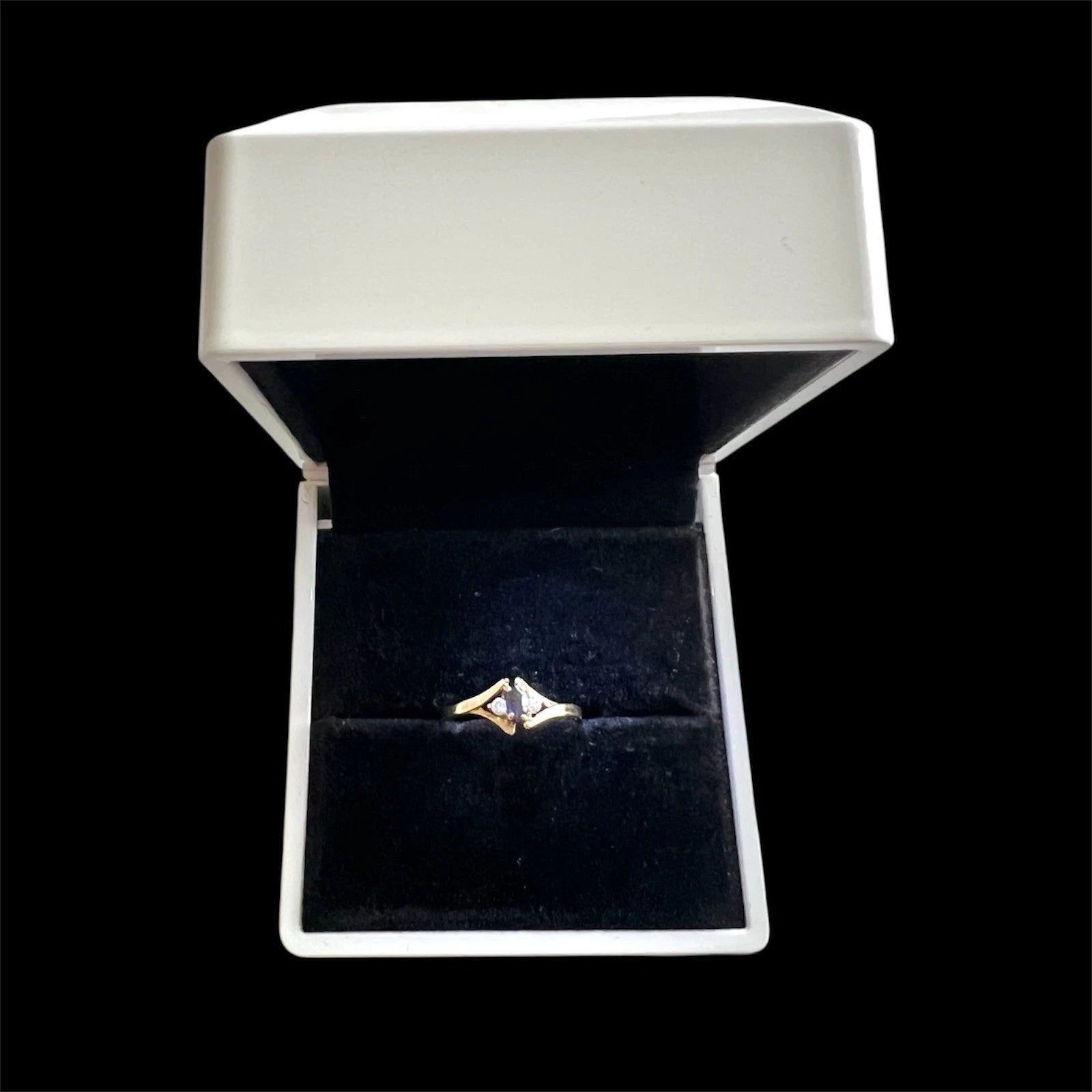 Gold ring with a sapphire and diamond in a white jewellery box on a white background