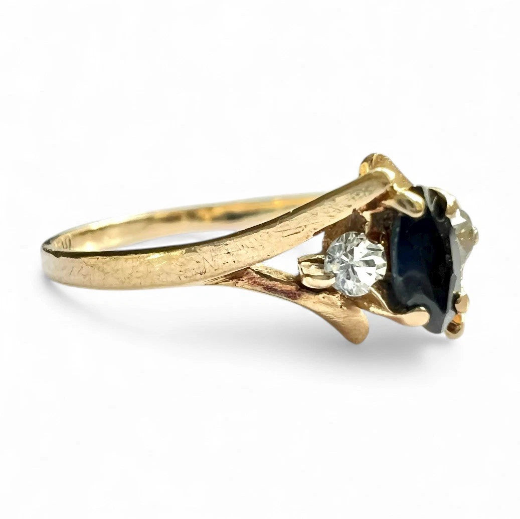 Gold ring with a sapphire gemstone and clear stone on a white background