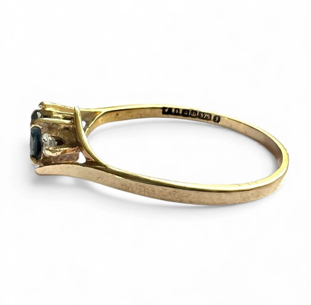 Gold ring with gemstone and visible hallmark on a white background