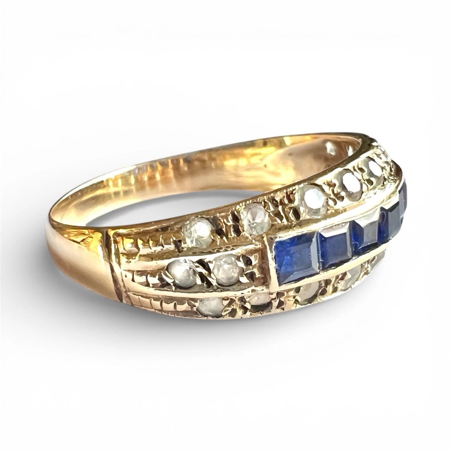 Gold ring with blue and white gemstones on a white background