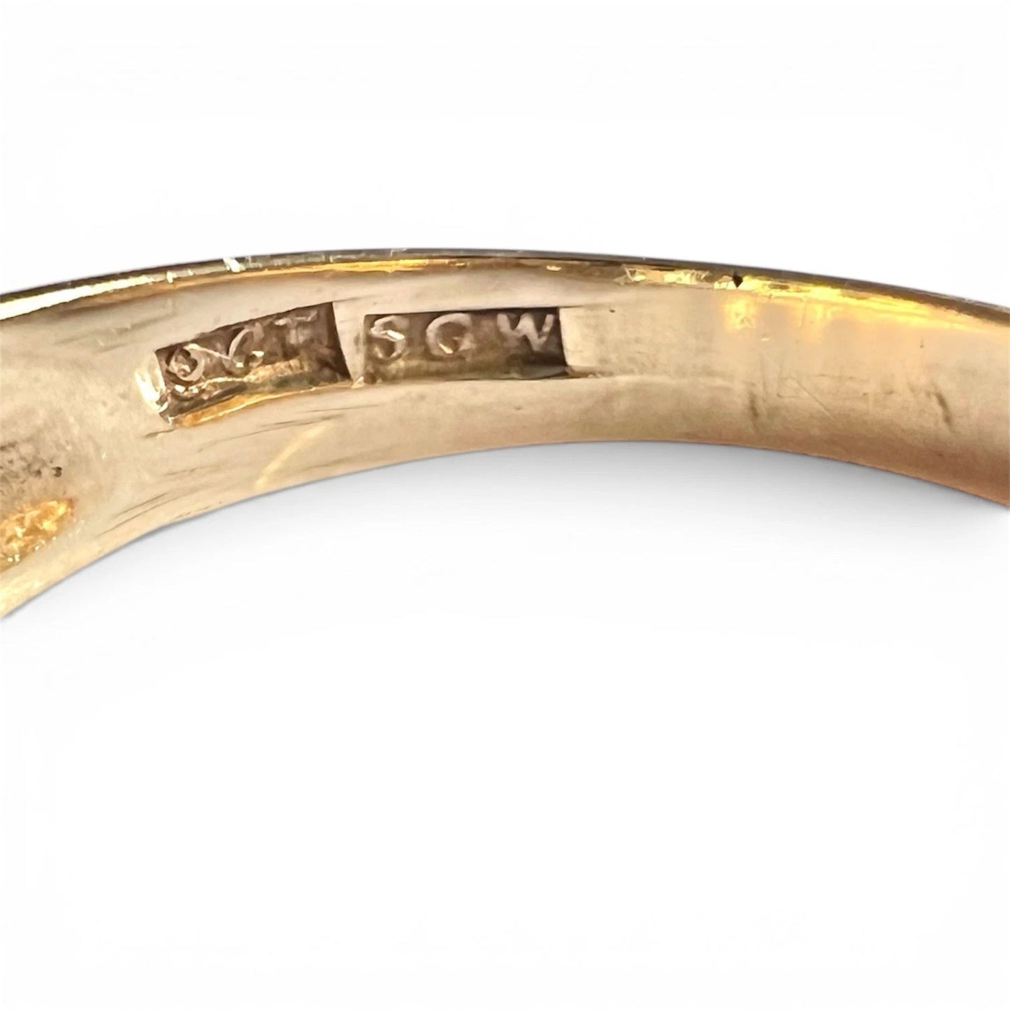 Close-up of a gold ring with engraved hallmark on a white background