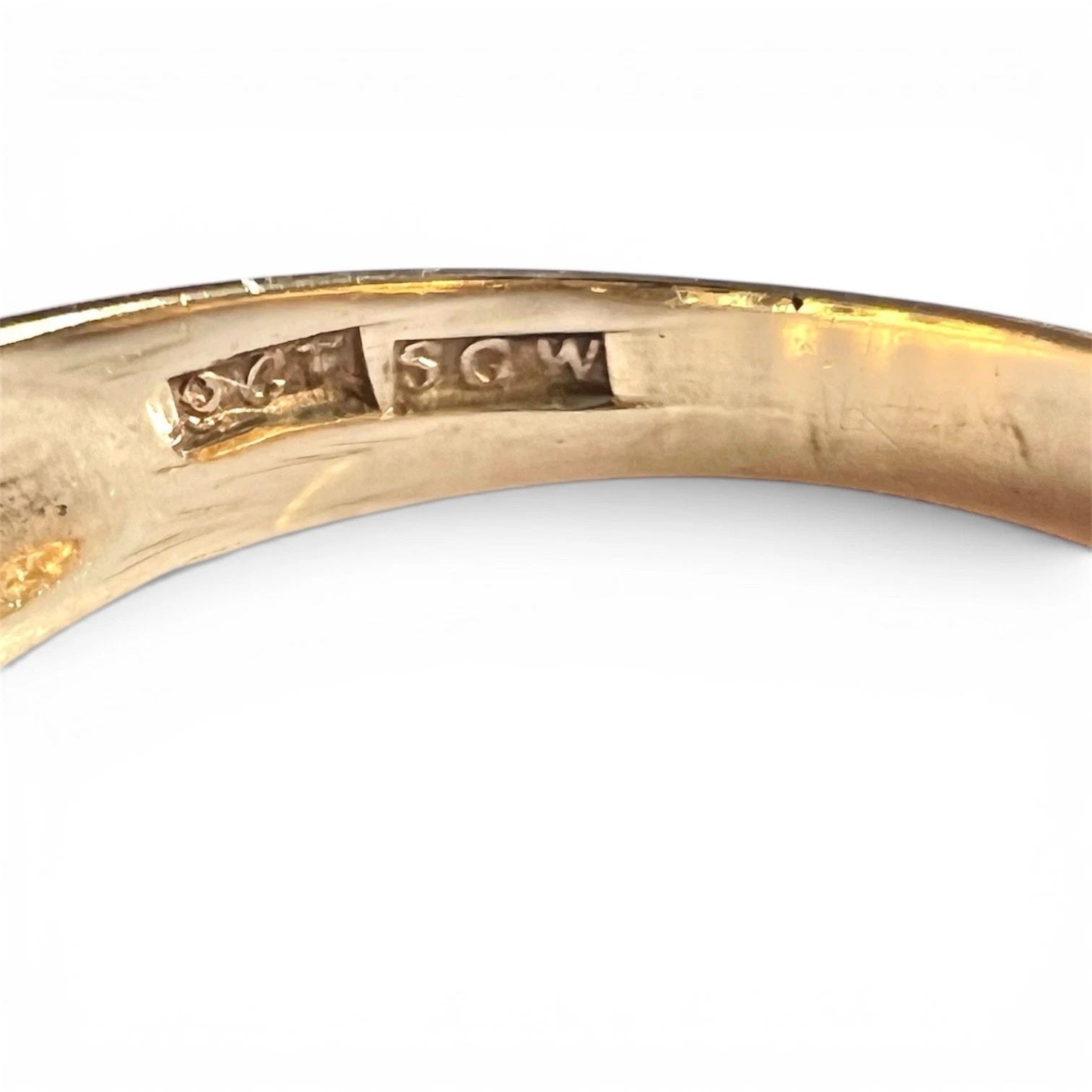 Close-up of a gold ring with engraved hallmark on a white background