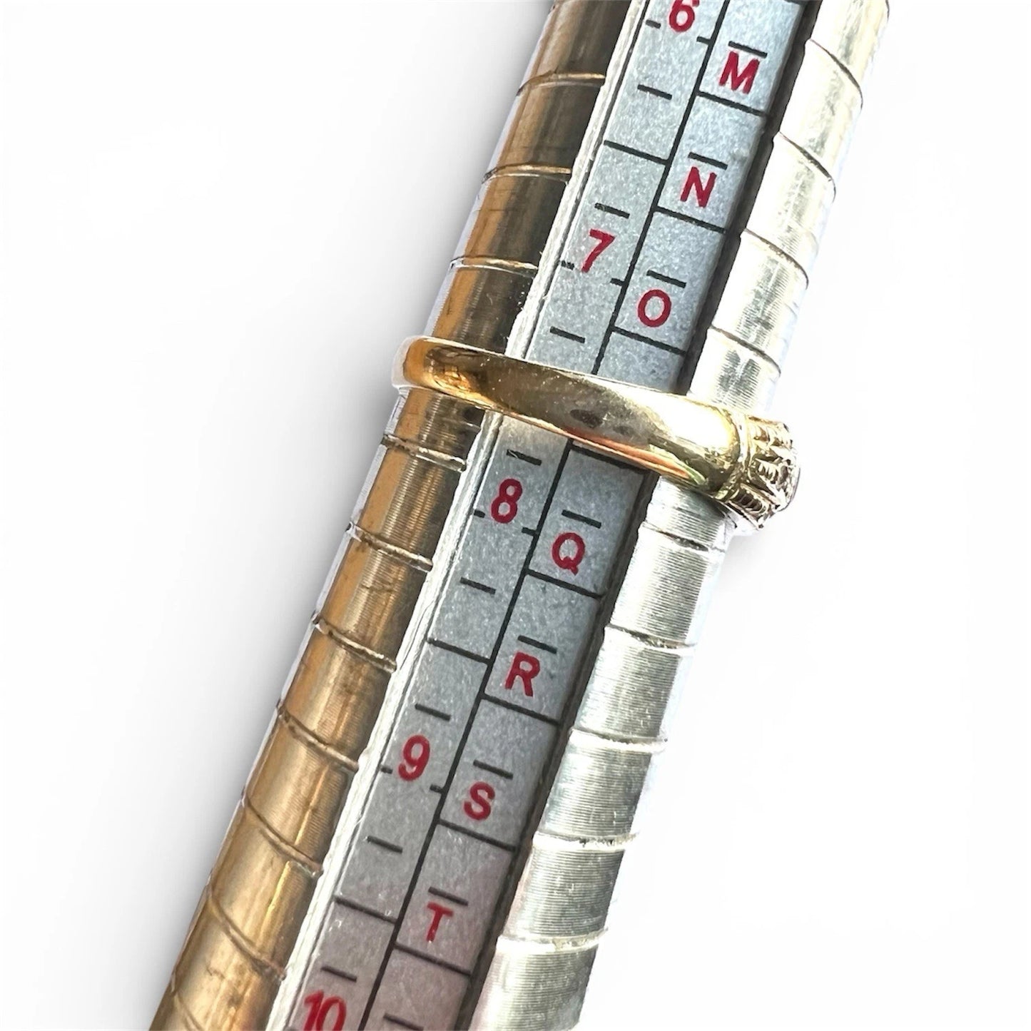 Close-up of a gold ring on a ring sizer gauge on a white background