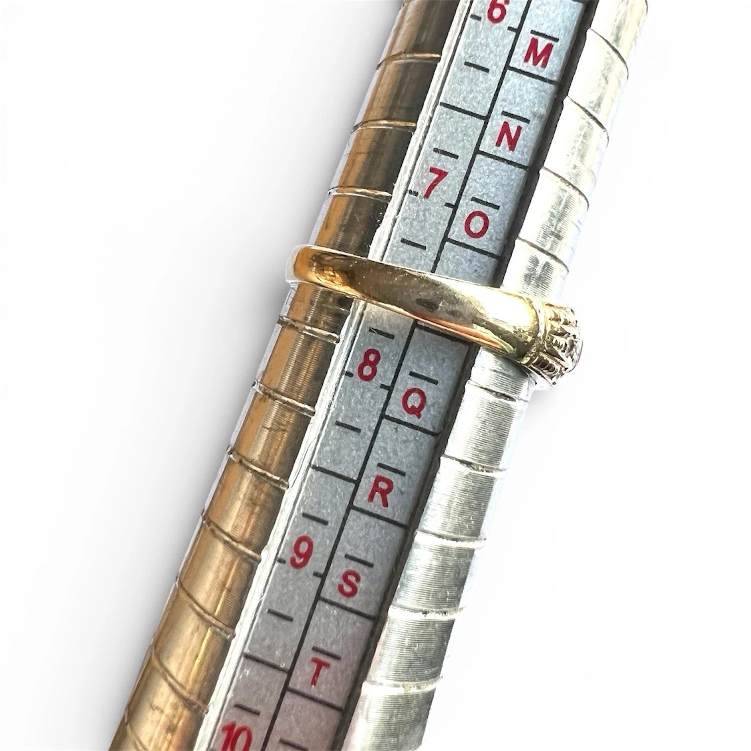 Close-up of a gold ring on a ring sizer gauge on a white background