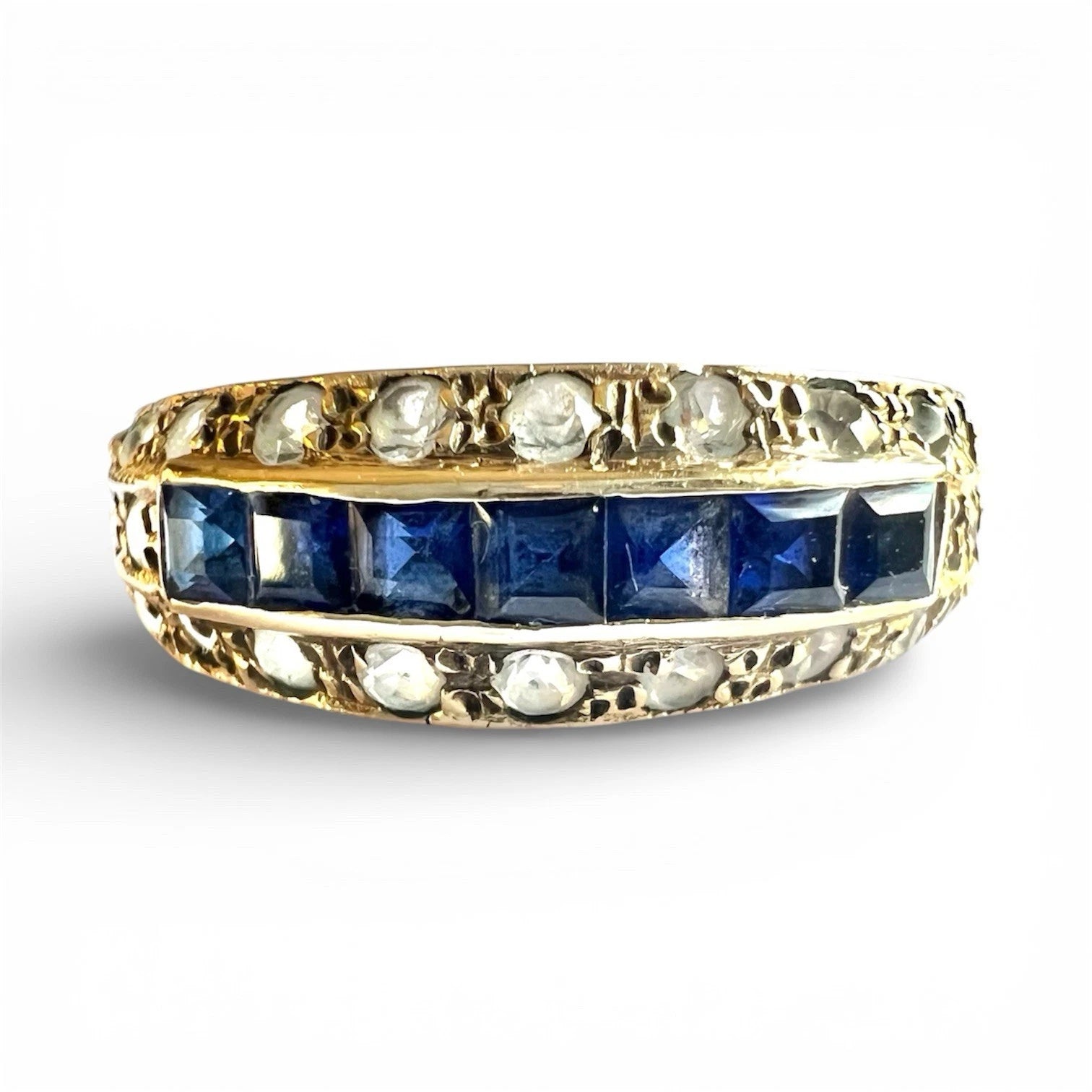 Gold ring with blue sapphires and cubic zirconia on a white background
