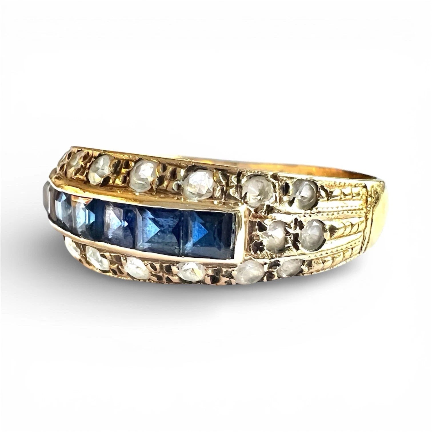Gold ring with blue sapphire gemstones and cubic zirconia on a white background